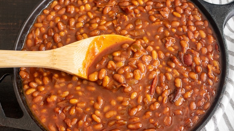 Top-down close-up of baked beans in a cast-iron pan with a spoon