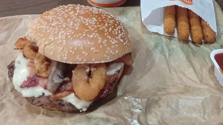 A Burger King Ultimate Steakhouse Whopper sitting on a table with mozzarella sticks