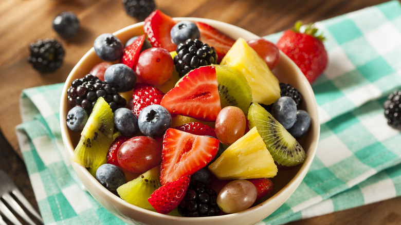 a bowl of fruit salad with strawberries, kiwi, blueberries, and grapes