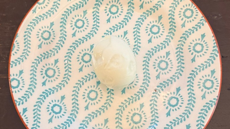 A pock-marked hard-boiled egg sits in the middle of a teal and white patterned plate