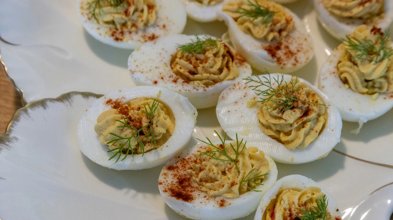 A coterie of deviled eggs garnished with dill and paprika