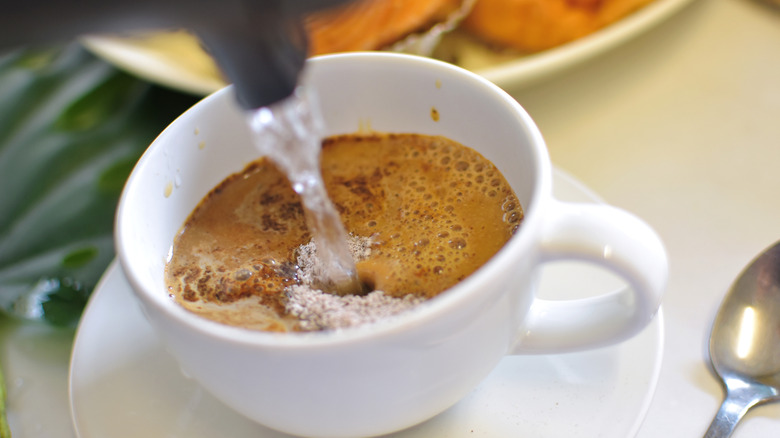 pouring hot water into an instant latte mix