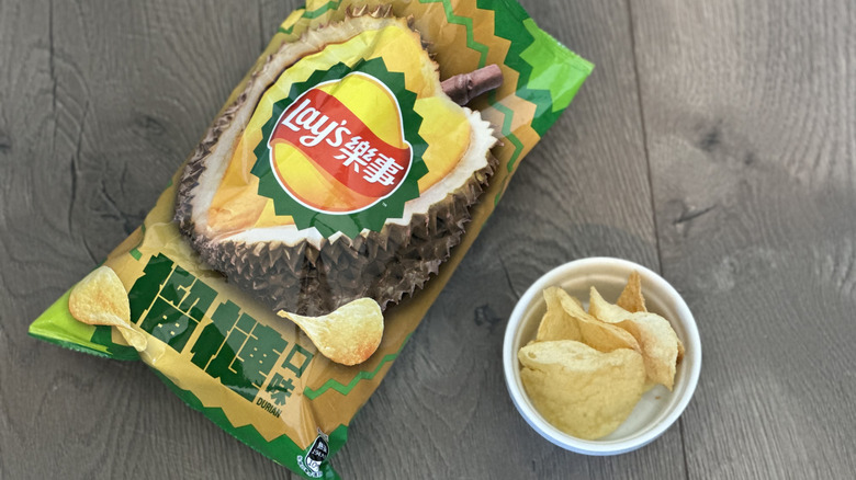 a bag of durian-flavored Lay's on a wooden table with a small ramekin of the chips beside it