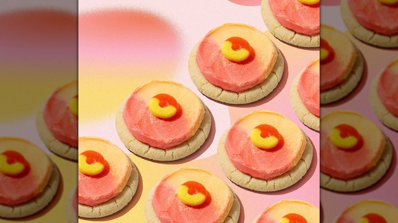 Crumbl Peach Ring Cookies arranged in rows on pastel pink and yellow background
