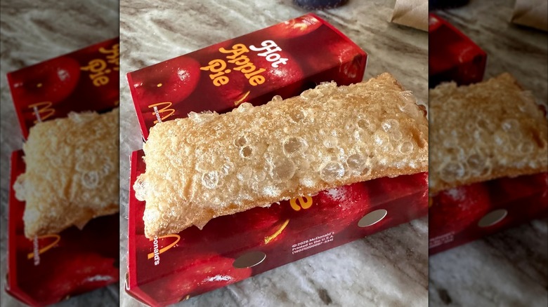 a bubbly McDonald's Fried Apple Pie resting atop its cardboard carton