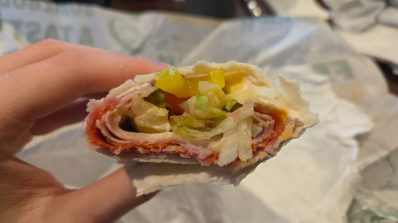 a hand holding a half-eaten Subway Italian Protein Pocket