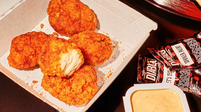 Diablo Dusted Crispy Chicken Nuggets in a cardboard barton next to various Taco Bell sauces