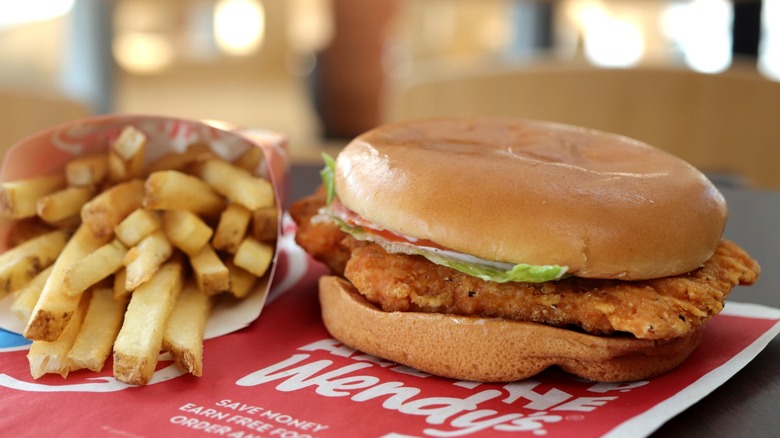 Wendy's Spicy Chicken Sandwich sitting on tray next to cardboard sleeve of french fries