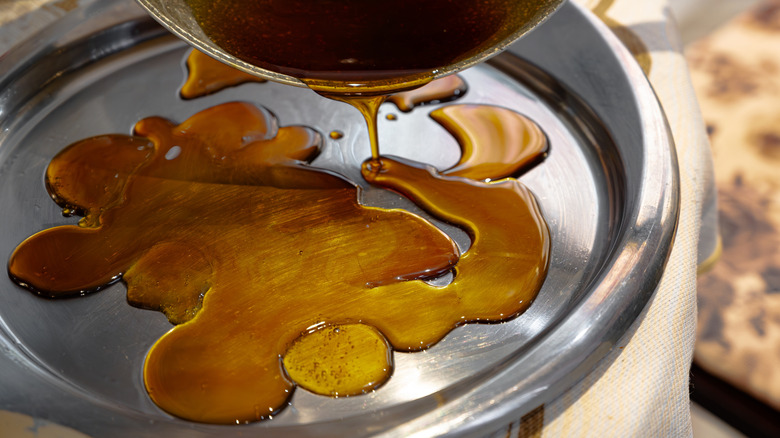 pouring caramel from a pot onto a metal dish