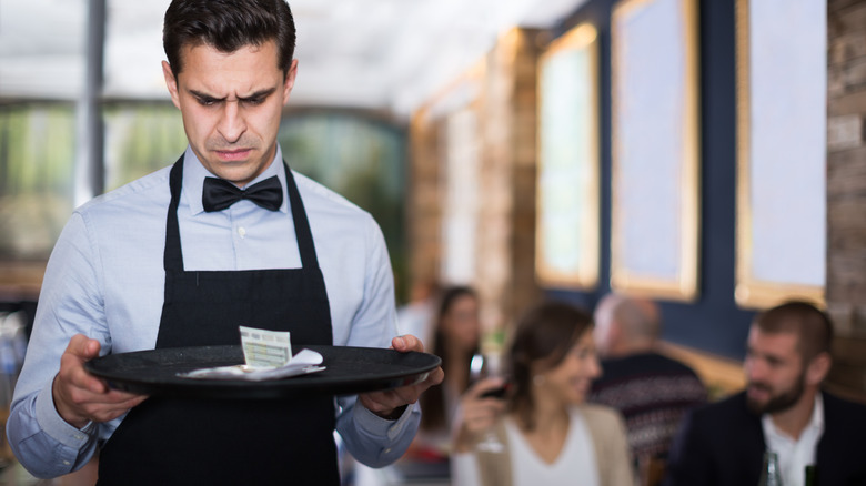 Waiter staring at a serving tray with a poor tip