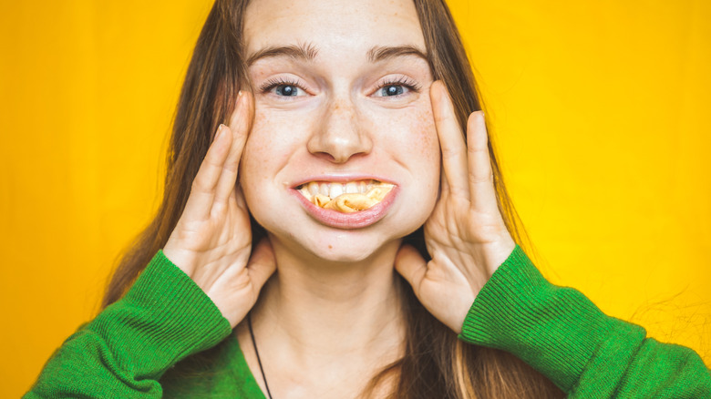 Woman smiling through a mouth full of food