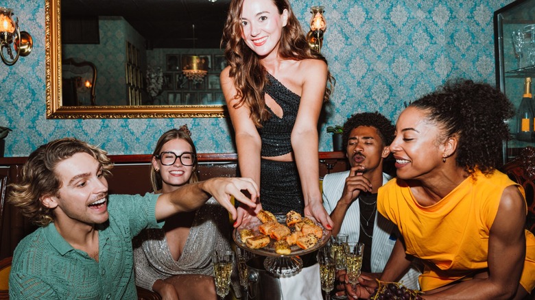 Waitress serving appetizers to a group of people