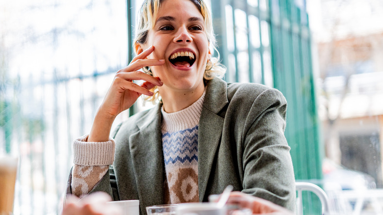 Woman laughing loudly at a table in a restaurant
