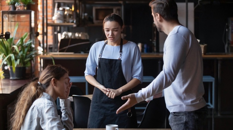 Woman embarrassed by her dining companion yelling at a waitress