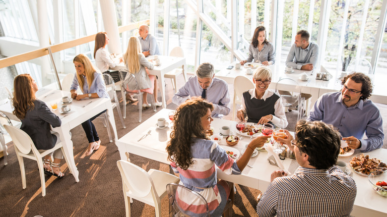 A high-angle view of the bright dining room of a busy restaurant with an open layout
