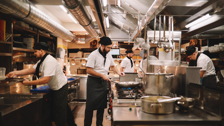 Employees working diligently on individual tasks inside a commercial kitchen