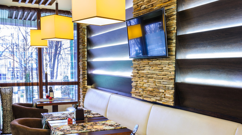 A modern restaurant interior with a TV hanging over one of the tables