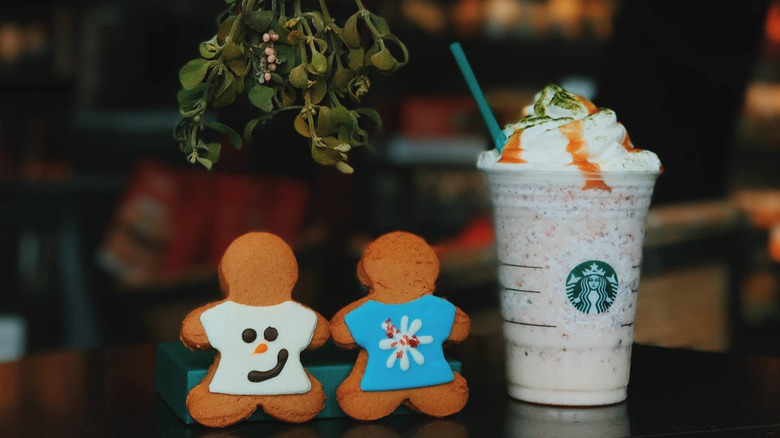 Two gingerbread men cookies beside a Starbucks Fruitcake Frappuccino