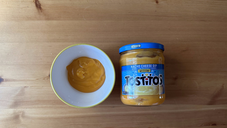 Tostitos Medium Nacho Cheese Dip in jar, next to a bowl of the dip