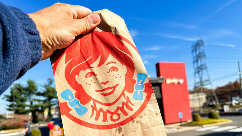 someone holding bag of wendy's food
