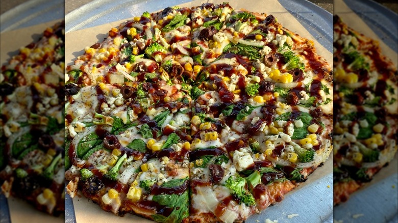 Pizza with sweet corn, broccoli, and BBQ sauce on a tray