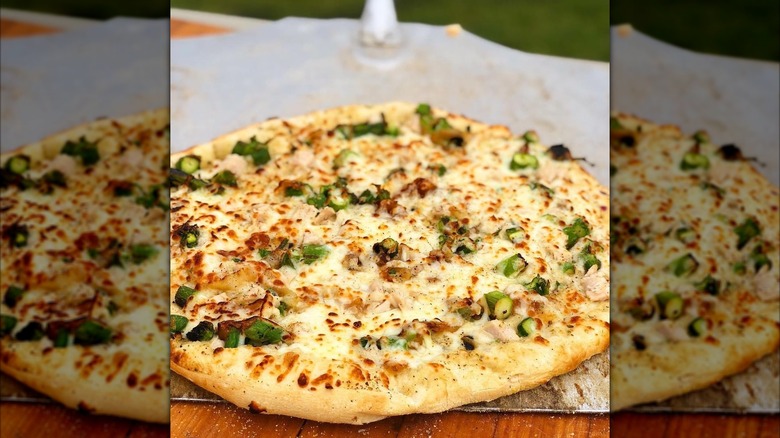 Cheese and onion pizza on a peel on a table outside
