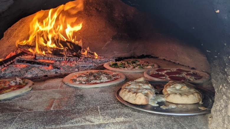 Several pizzas cooking in a blazing brick oven