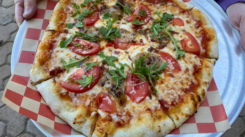 Pizza with slices of tomatoes on a silver tray