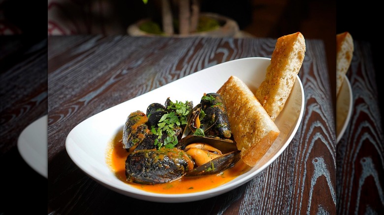 Dish of steamed mussels on wooden table