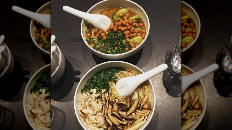Two bowls of soup and noodles on black table