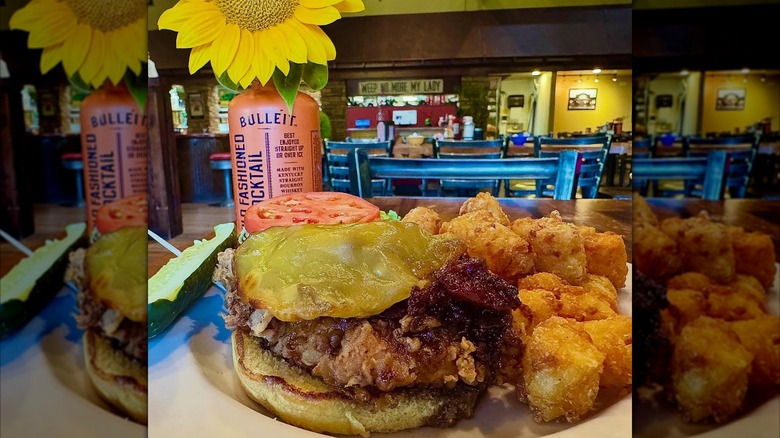 Fried chicken sandwich with cheese and tots on a plate