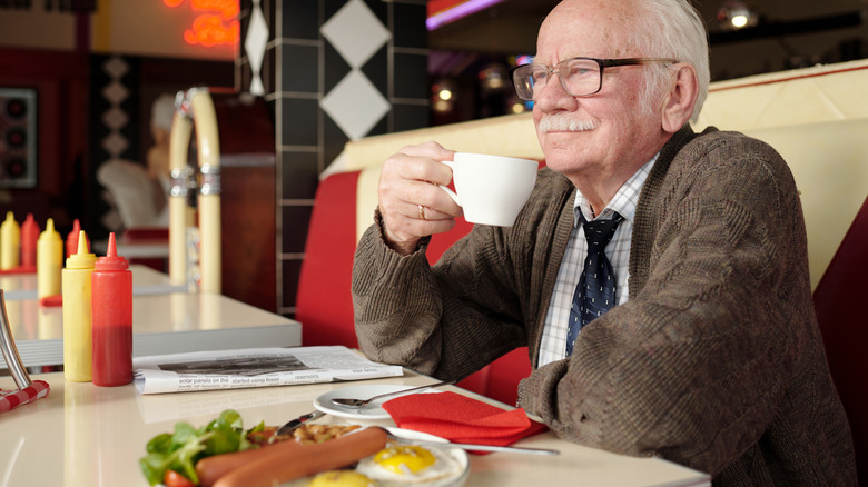 Older man drinking coffee at a retro diner
