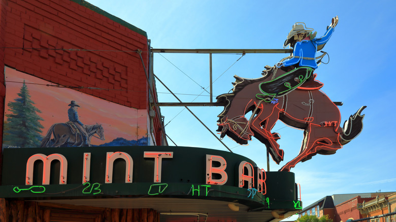 A neon cowboy sign in front of the Mint Bar