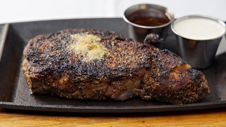 Caramelized prime rib slice on iron tray with au jus and horseradish