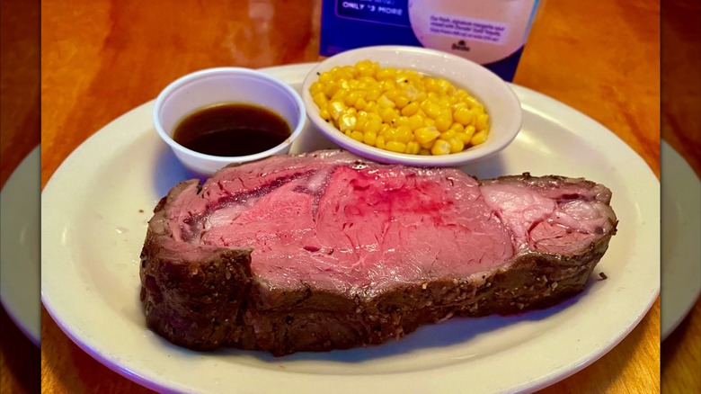 Prime rib on plate with au jus and corn