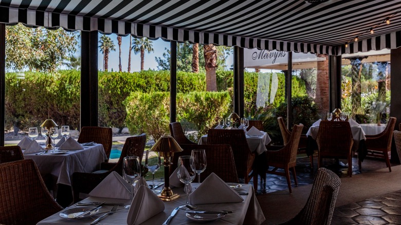 Tables in an enclosed patio with an awning on a sunny day at Melvyn's