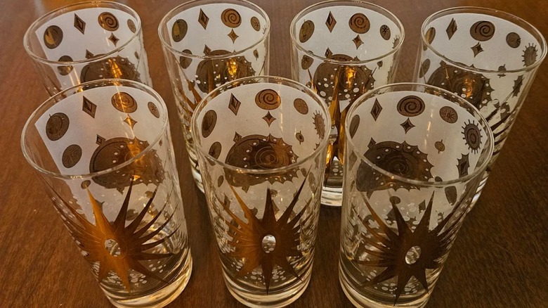 Seven Fred Press glasses with a gold-and-white atomic design