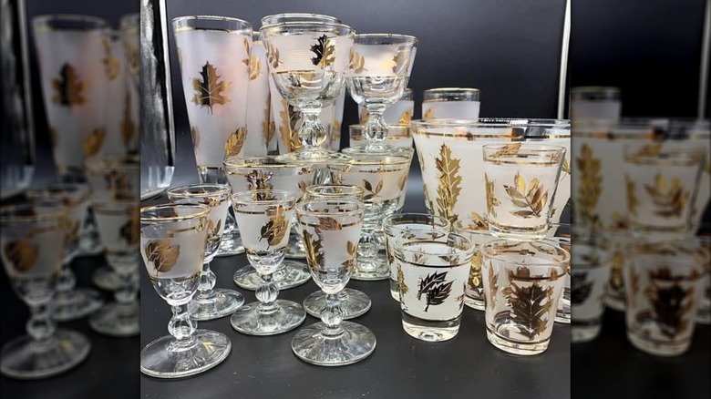Collection of Libbey barware in a display case with various frosted glasses decorated with gold