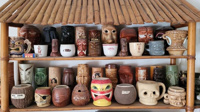 Collection of assorted vintage tiki mugs in a bamboo display