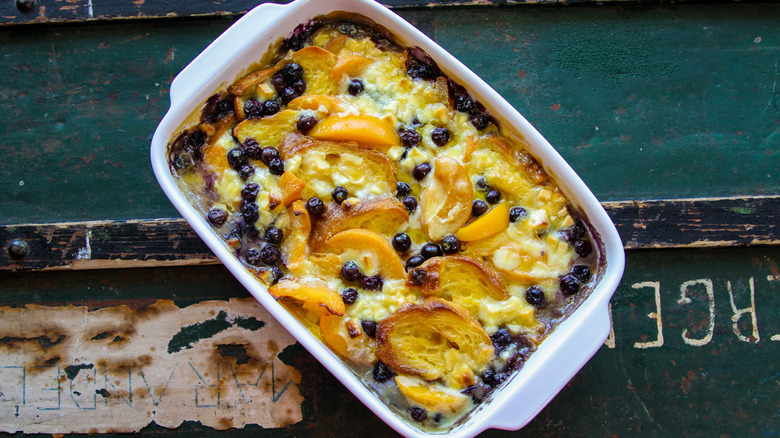 peach and blueberry bread pudding in white baking dish