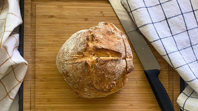 Crusty Italian loaf of bread on a wooden board with a bread knife