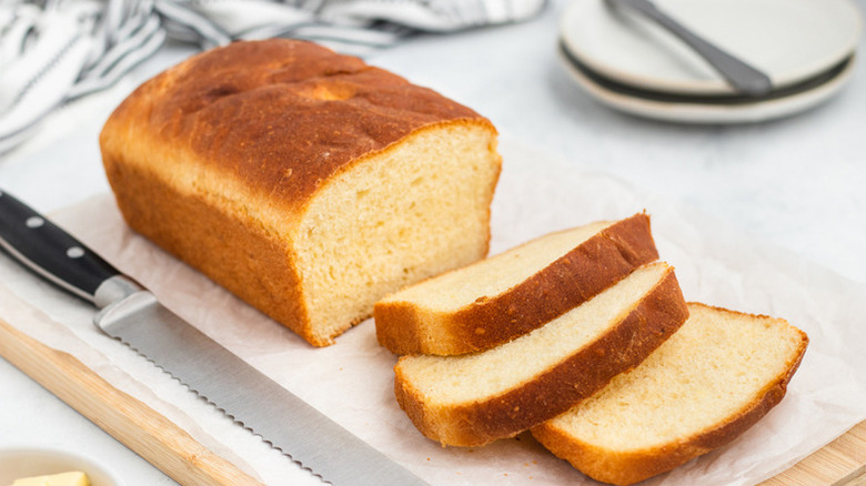 Sliced loaf of fluffy potato bread on a parchment-lined wooden board