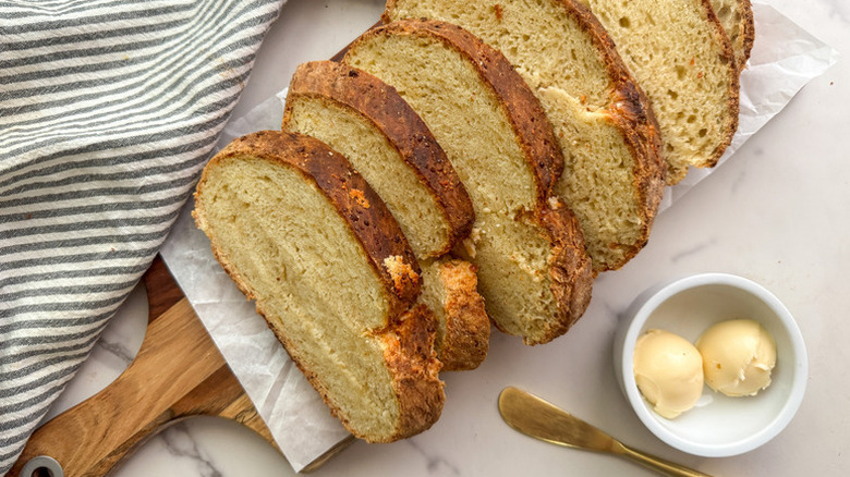 Sliced asiago bread on a parchment-lined wooden board