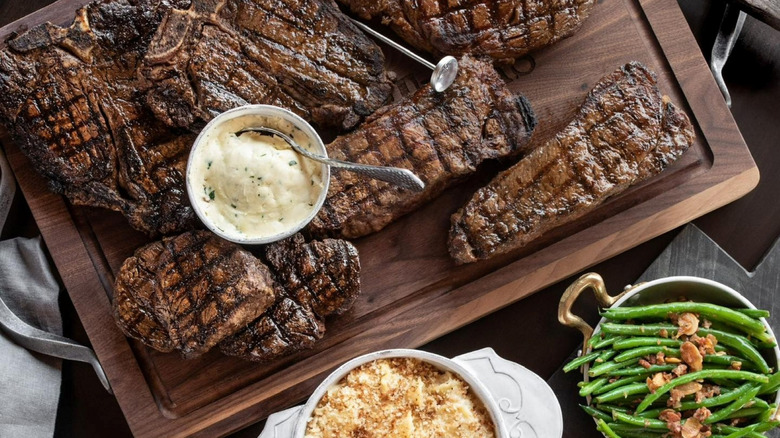 a spread of steaks on a cutting board, mashed potatoes, and sides from Taste of Texas
