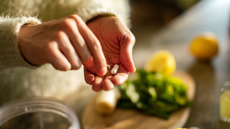 Close up of supplements in woman's hands, with kitchen in background