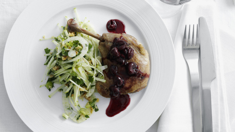 a piece of chicken with cranberry compote next to a fresh slaw