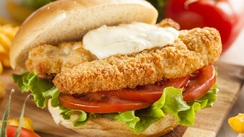 A fried catfish sandwich with lettuce and tomato on a bun