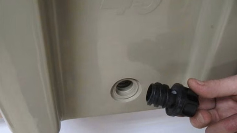 A hand holding a plug near a Yeti cooler