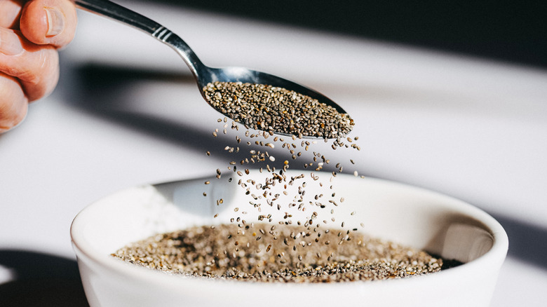 person putting chia seeds into bowl