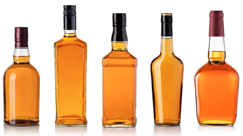 Five whiskey bottles, white background